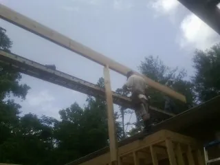 Carpenter setting a ridge beam over a new addition frame — Ice Dam Removal by Roofing Brothers in May