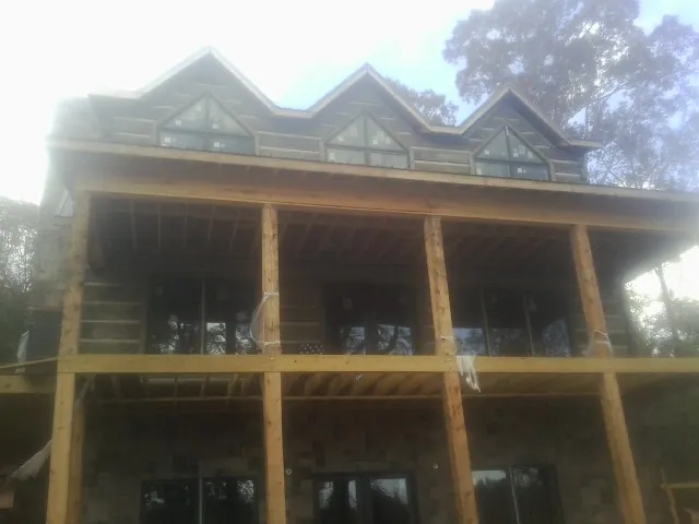 Dormers and porch framing on a large log home under construction — Roof Coating work by our crew in May