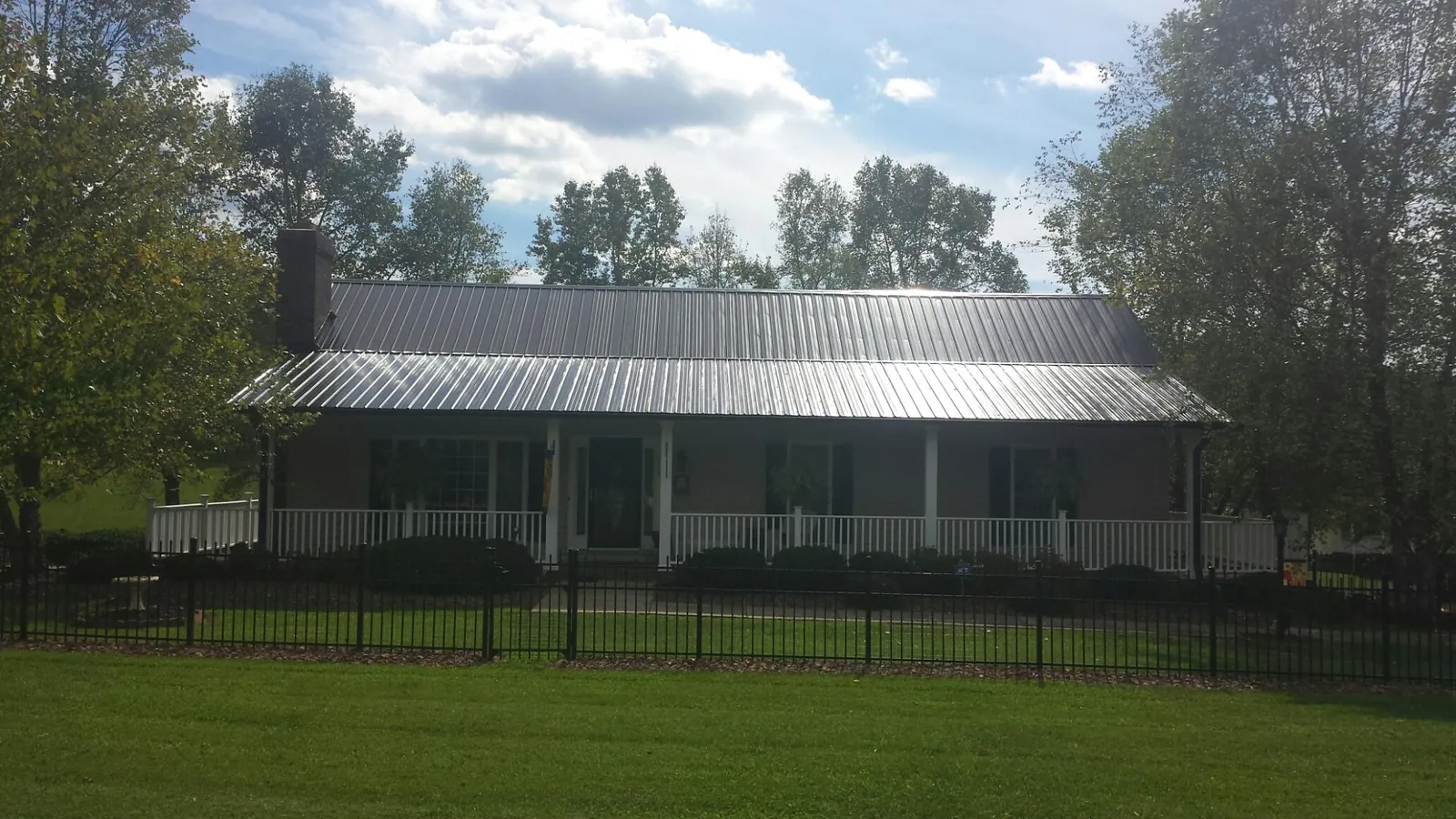 Gray metal roof on a brick ranch with a full width front porch — Gutter Guard Installation work by our crew in May