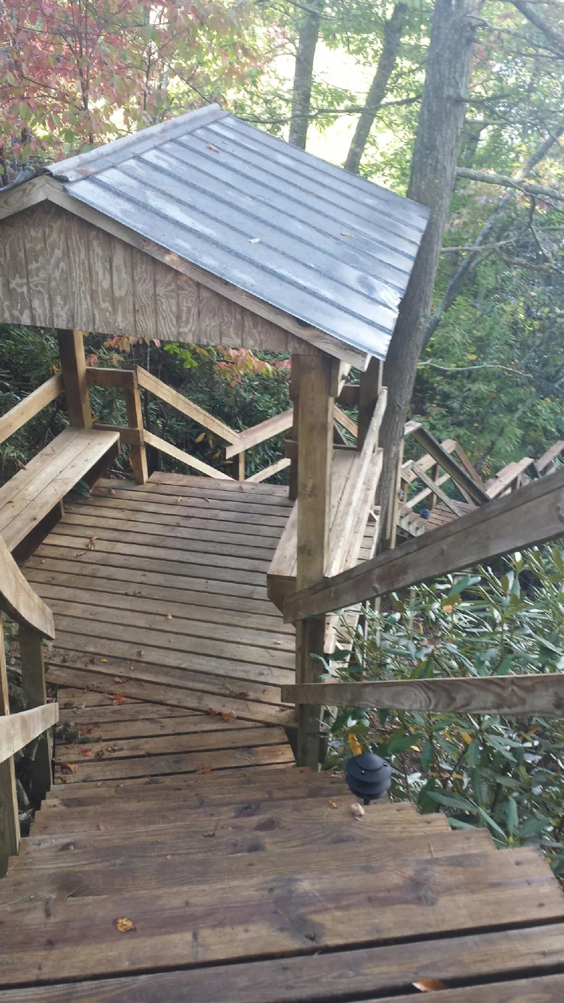 Metal roofed shelter over wooden steps on a wooded walkway — Skylight Repair & Installation work by our crew in May