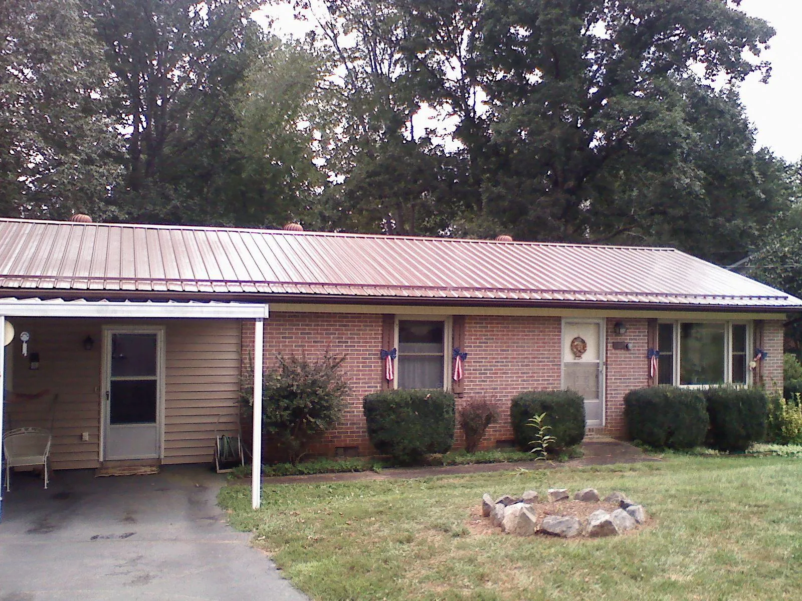 Bronze metal roof and carport on a brick ranch home — Roof Repair work by our crew in May