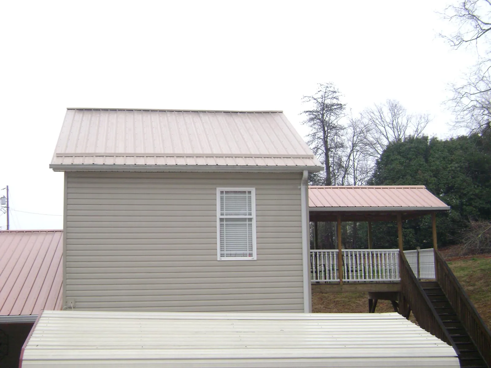 Tan metal roofs on a two story addition and attached porch, from a Roof Replacement job in May